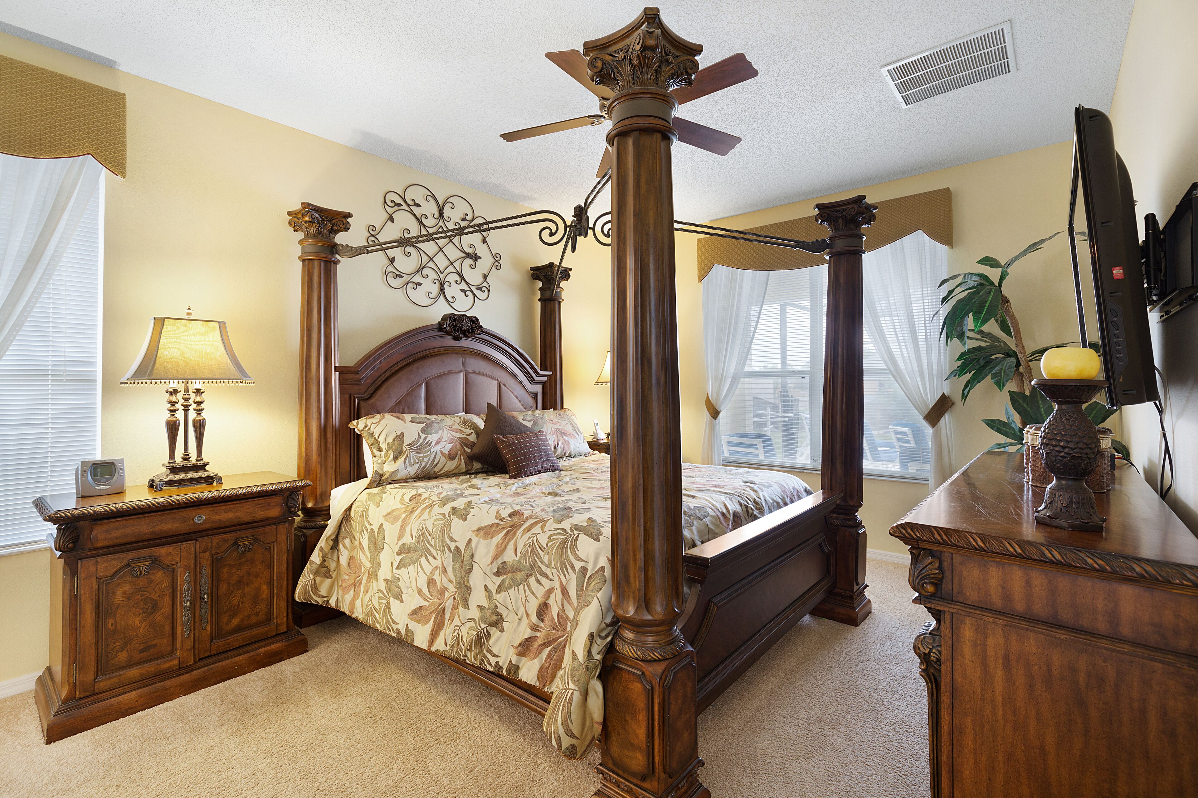 A four-poster bed with a headboard, a bedside table with a lamp, and a television on a stand.