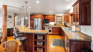 Enjoy cooking in this well-equipped kitchen with a large island, stainless steel appliances, and wooden cabinetry.