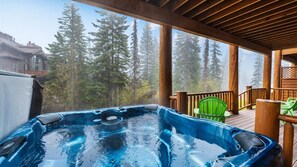 A hot tub on a wooden deck with a view of tall trees. - Big Mountain Chalet: Ski-In/Ski-Out Townhome with Private Hot Tub (Whitefish)