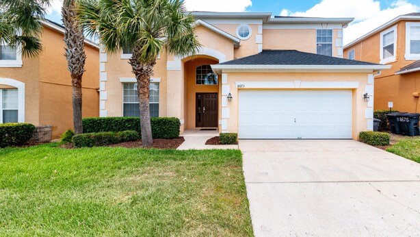 A two-story house with a garage, palm trees, and a well-maintained lawn. - Timeless Memories by VillaDirect (Kissimmee)