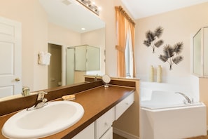 A bathroom with a sink, mirror, vanity, and bathtub. - Timeless Memories by VillaDirect (Kissimmee)