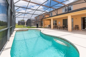 Una piscina con cerramiento de vidrio, zona de estar exterior y vistas del paisaje circundante.