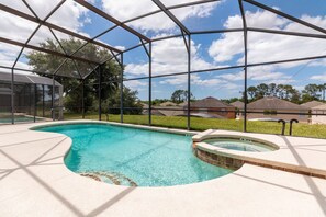 A swimming pool with a glass enclosure, surrounded by a patio area. - Timeless Memories by VillaDirect (Kissimmee)