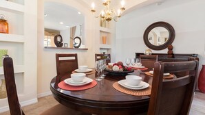 A dining area with a round table set for four, surrounded by wooden chairs. - Timeless Memories by VillaDirect (Kissimmee)