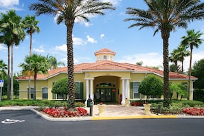 A yellow building with a red-tiled roof, palm trees, and red flowers. - Timeless Memories by VillaDirect (Kissimmee)
