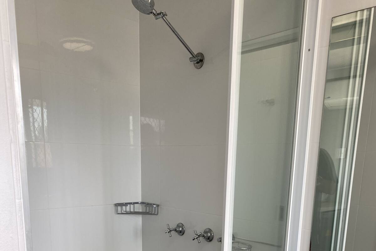 Un baño con ducha, lavabo y espejo.