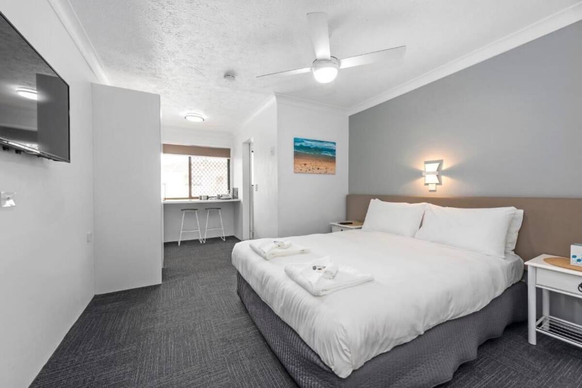Una habitación de hotel moderna con una cama grande, un escritorio y una televisión.