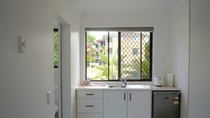 A compact kitchen with a window, a sink, and a refrigerator. - Gold Coast Inn (Surfers Paradise)