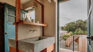 A bathroom with a concrete sink, wooden cabinets, and a large mirror. - Waye Valladolid Centro – Sustainable, Authentic Experiences & Pet Friendly Boutique Hotel (Valladolid)