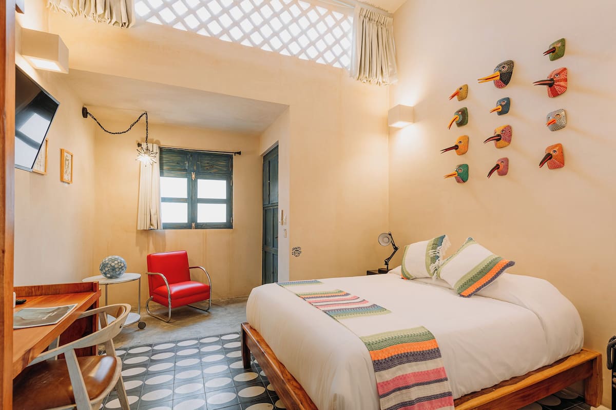 Un dormitorio con cama, escritorio, silla, ventana y decoración en la pared.