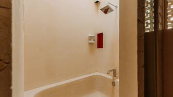 A bathroom with a bathtub, a showerhead, and a towel rack.