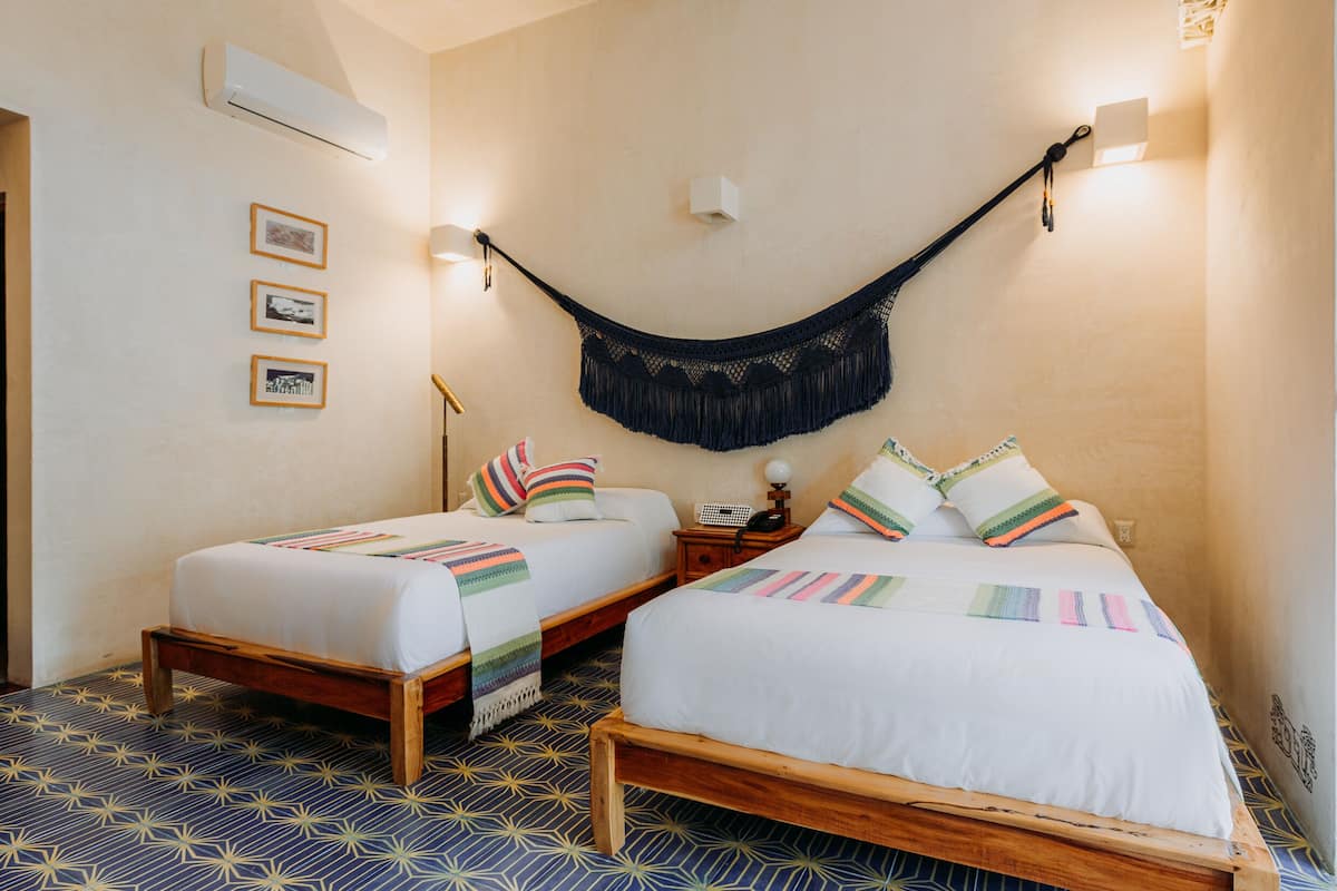 A room with two wooden beds, a hammock, and a patterned floor.