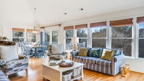 A spacious living room with a dining area, large windows, and a cozy seating arrangement. - Bluebird: Saltwater Pool, Hot Tub. Golf Community (Corolla)