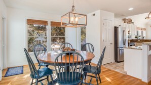 A dining area with a round table, six chairs, and a hanging light fixture. - Bluebird: Saltwater Pool, Hot Tub. Golf Community (Corolla)