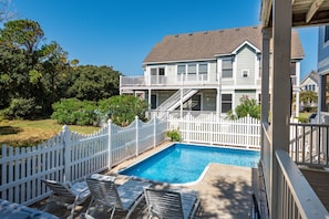 A two-story house with a swimming pool, white picket fence, and outdoor seating area.