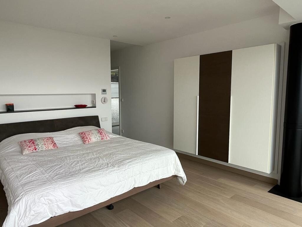 Un dormitorio moderno con una cama grande, un armario y una estantería con objetos decorativos.