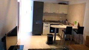 A modern kitchen with a dining area, a trash bin, and a small table with chairs. - 1 bedroom apartment in agadir (Agadir)
