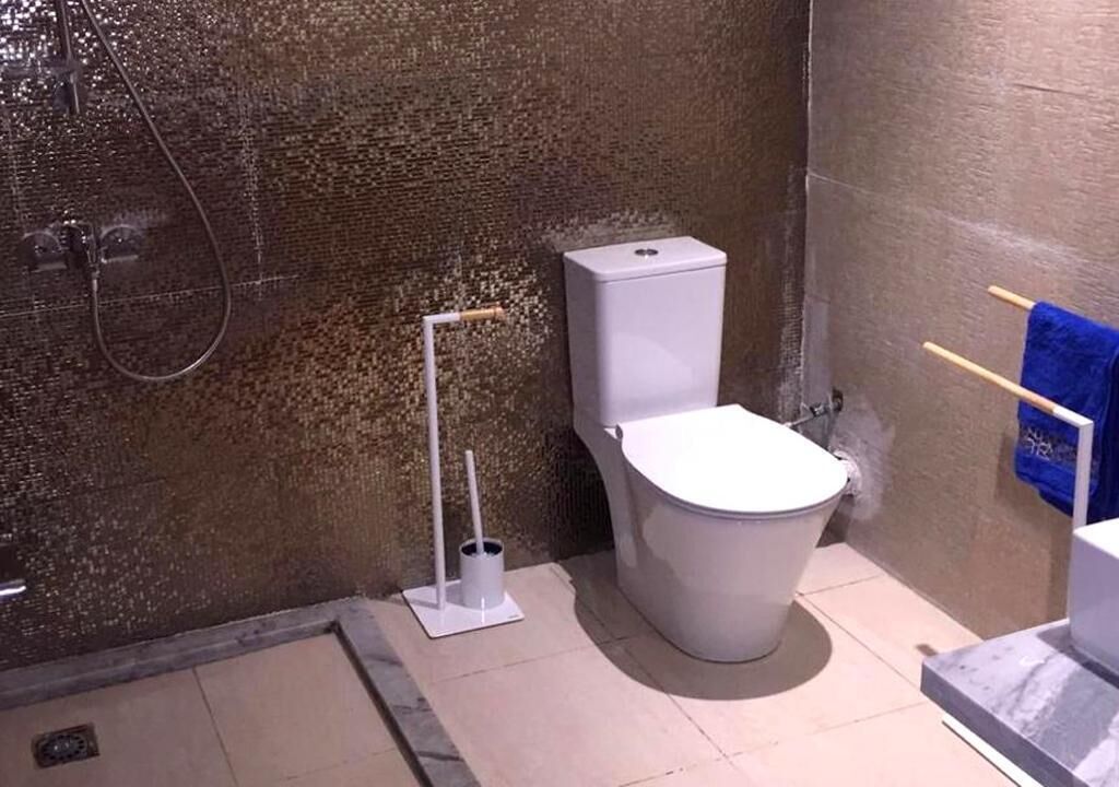 A bathroom with a white toilet, a shower, and a blue towel rack.
