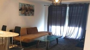 A living room with a glass coffee table, a sofa, a dining table with chairs, and a painting on the wall. - 1 bedroom apartment in agadir (Agadir)