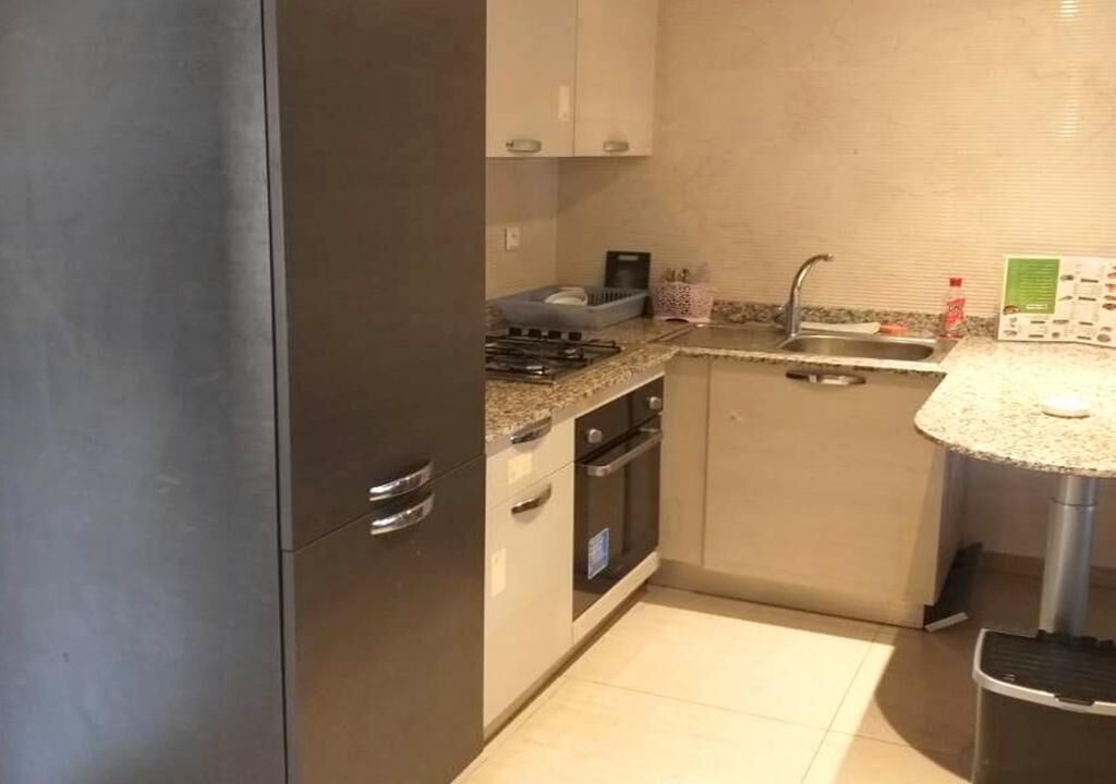 Eine kleine Küche mit Kühlschrank, Herd, Backofen und Spüle.