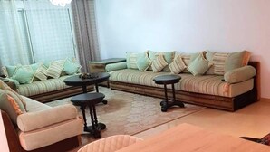 A living room with a sofa set, two side tables, and a dining table. - 2 bedroom apartment in agadir (Agadir)
