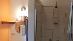 A bathroom with a sink, mirror, and shower.