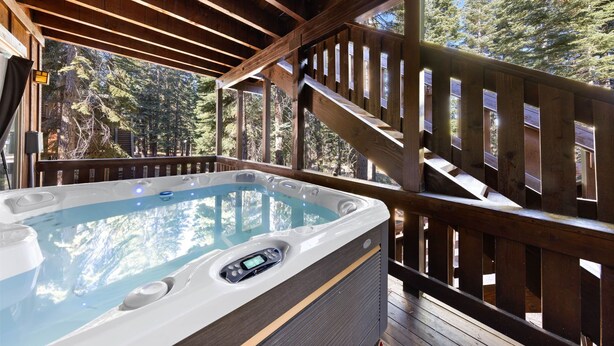 Un jacuzzi en una terraza de madera con vistas a los árboles.