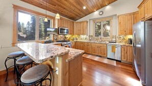 Una cocina con armarios de madera, encimeras de granito, un refrigerador de acero inoxidable y una isla grande con taburetes de bar.