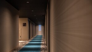 Un long couloir étroit, doté d’une moquette bleue, de murs en bois et d’un plafond pourvu d’un éclairage encastré.