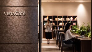 Un intérieur moderne avec un comptoir d’accueil, une bibliothèque et une enseigne indiquant « Café VISTA ».
