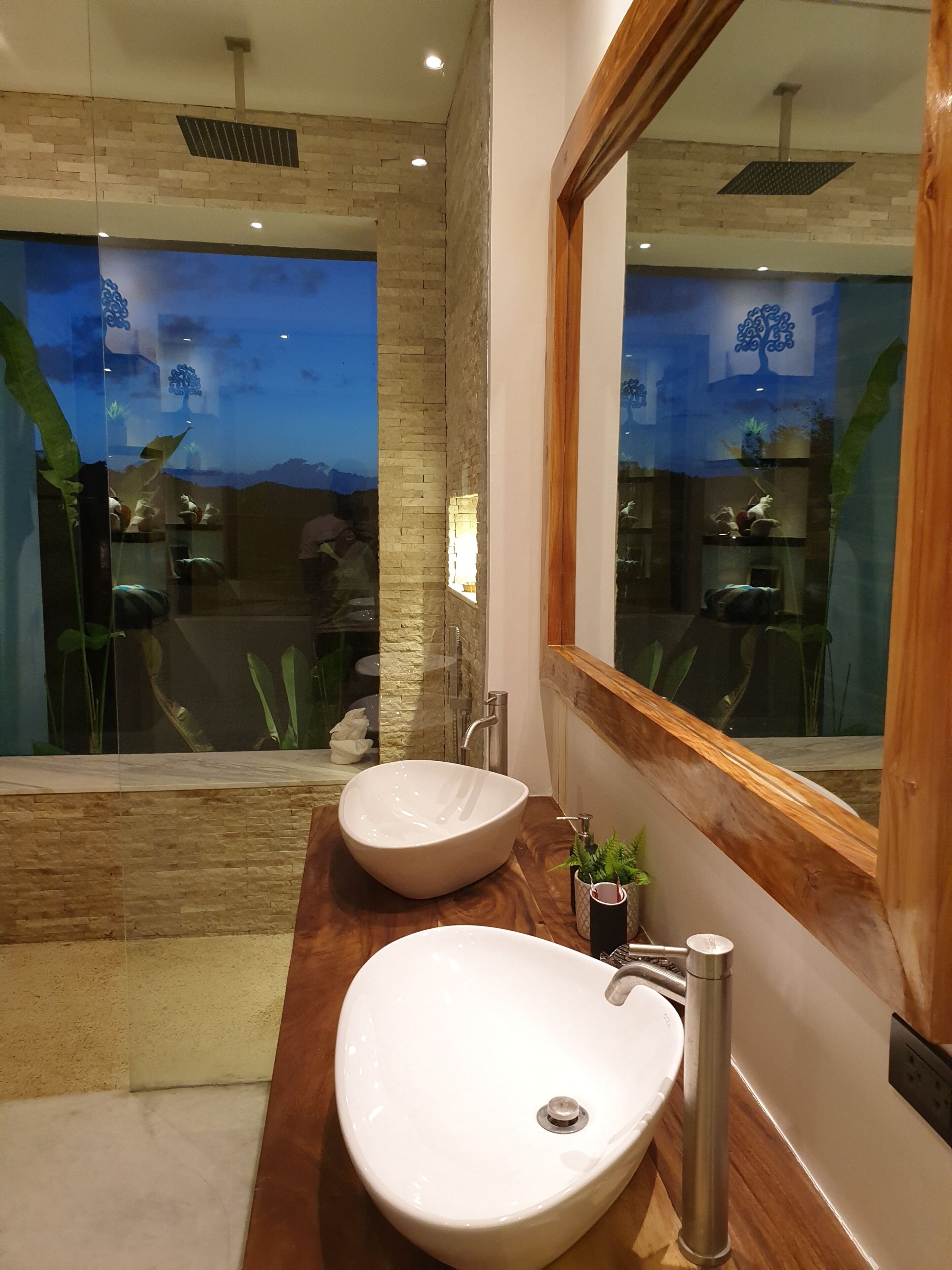 Een moderne badkamer met een grote spiegel, twee wasbakken en een douche.