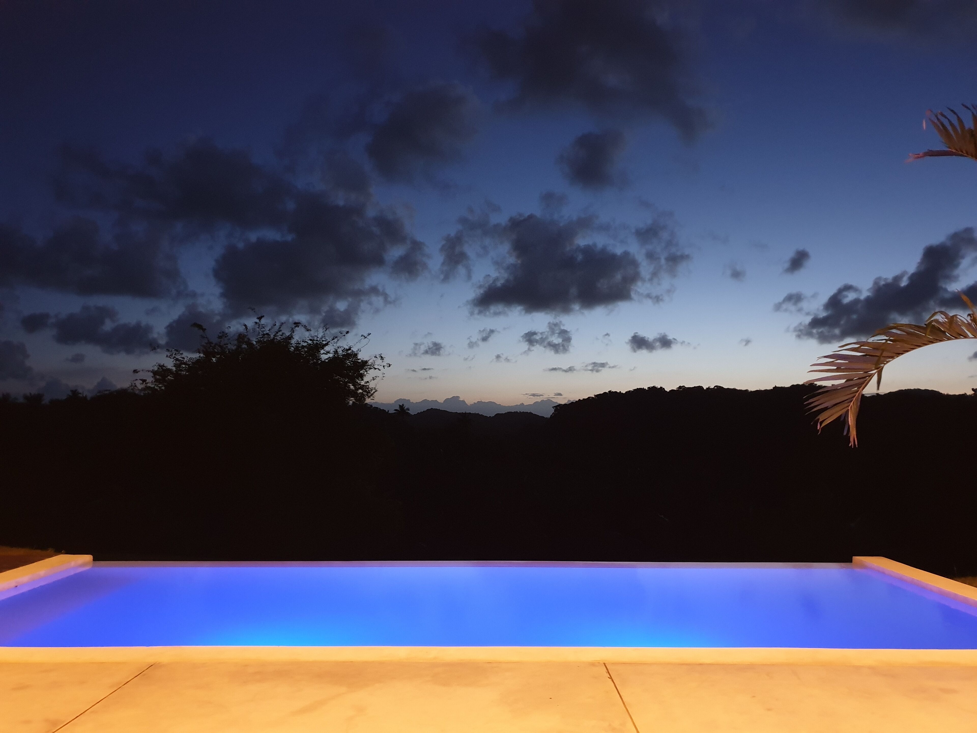 Une piscine offrant une vue sur le ciel et les collines lointaines.