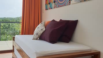 Quarto com cama de madeira, cortinas laranja e duas obras de arte coloridas nas paredes.