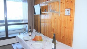 A dining table set with plates, glasses, and a bottle, in a room with wooden walls and a window.