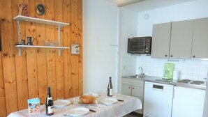 A kitchen with a dining table set for four, a microwave, a coffee maker, and a dishwasher.