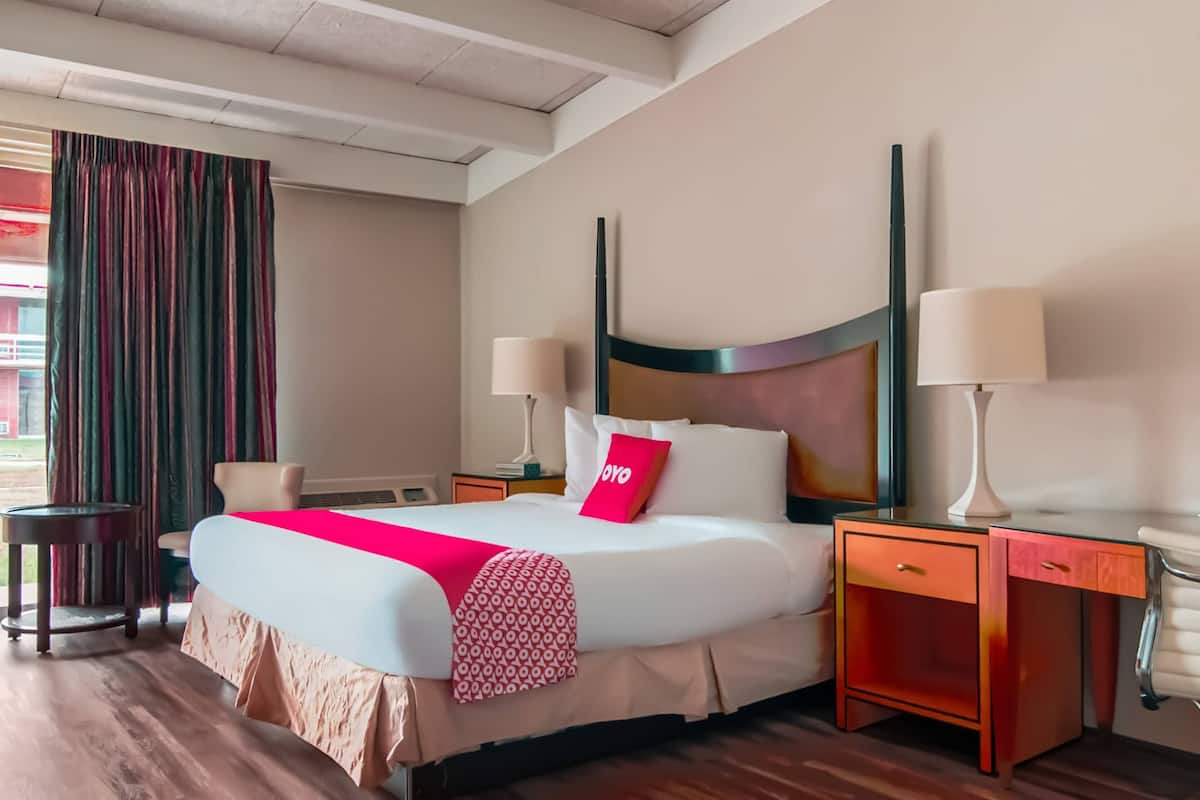 Une chambre d’hôtel avec un grand lit, deux tables de chevet avec des lampes, un bureau et une chaise.