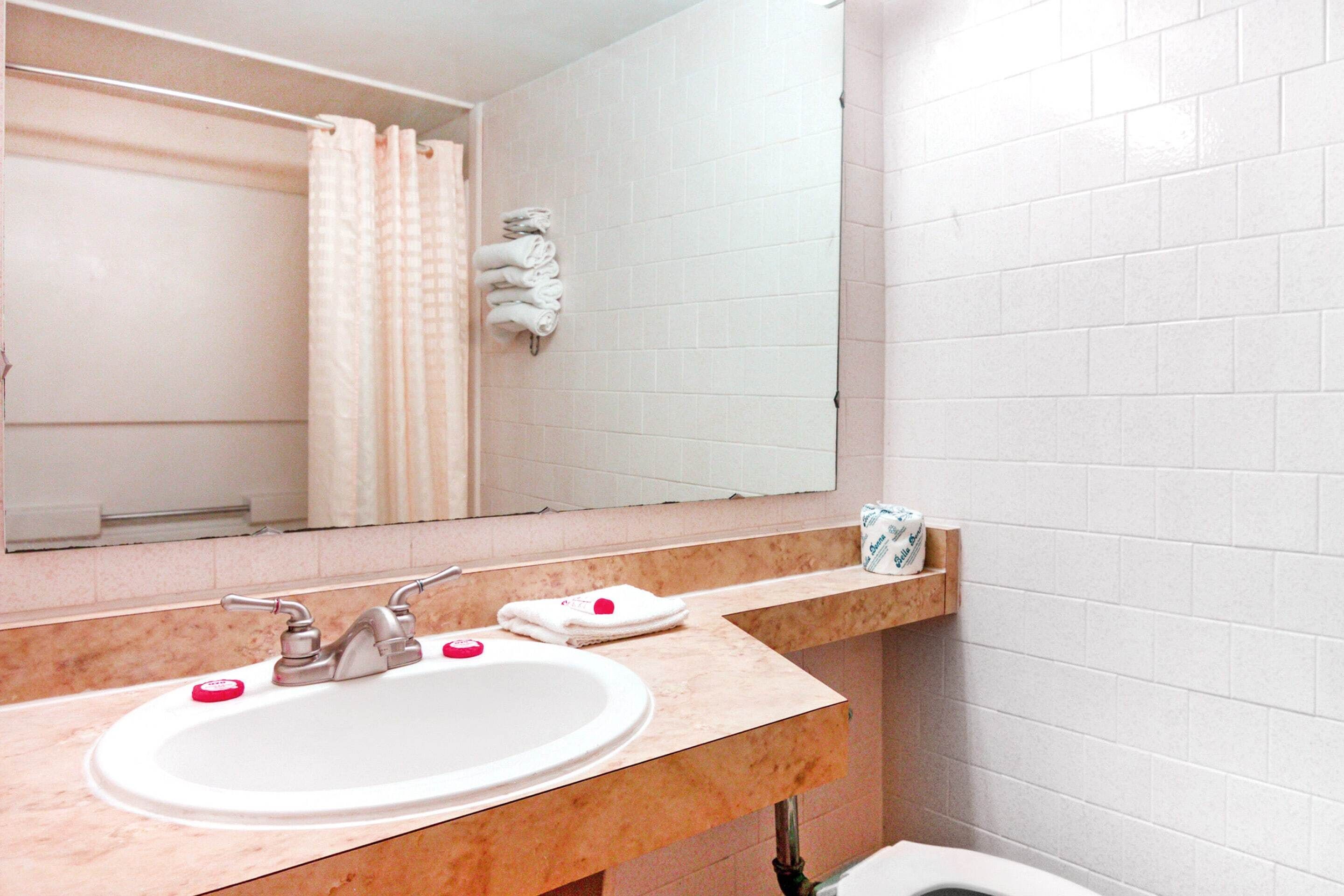 Un baño con lavamanos blanco, espejo y perchero.