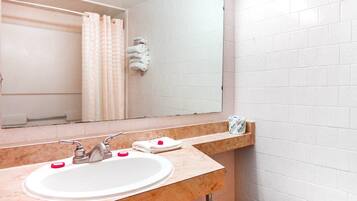 Un baño con lavamanos blanco, espejo y perchero.