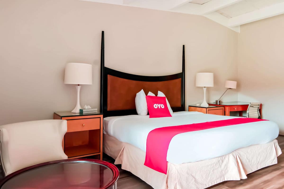 Une chambre d’hôtel avec un lit, deux tables de chevet, une chaise et une petite table.