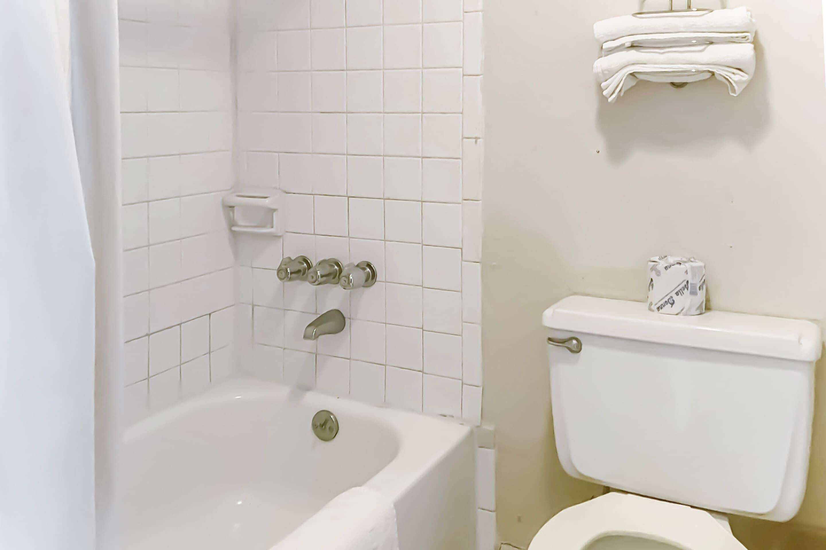 Ein Badezimmer mit Badewanne, Toilette und einem Ablagebereich mit Handtüchern.