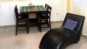 A dining area with a table and chairs, a chandelier, a wall with butterfly decals, and a black lounge chair.