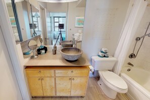 Un baño con tocador de madera, dos lavamanos de cerámica, inodoro blanco y bañera.