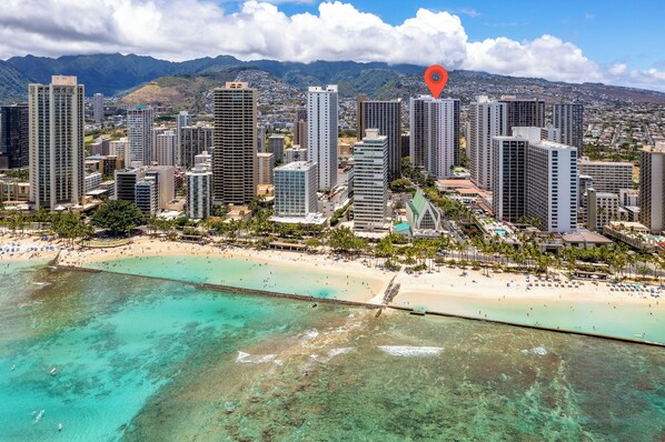 A coastal cityscape with high-rise buildings, a beach, and a clear view of the ocean.