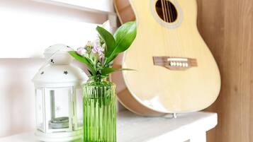 A white shelf with a green vase and a white lantern. A guitar is visible in the background.