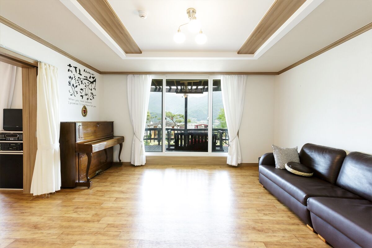 Un soggiorno con un pianoforte, un divano e vista su un balcone.