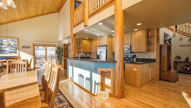 A spacious kitchen with wooden cabinets, a central island, and a dining area with a wooden table and chairs.