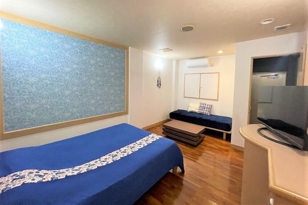 Una habitación de hotel pequeña con una cama individual, un sofá, un televisor y un ventanal con vistas decorativas.