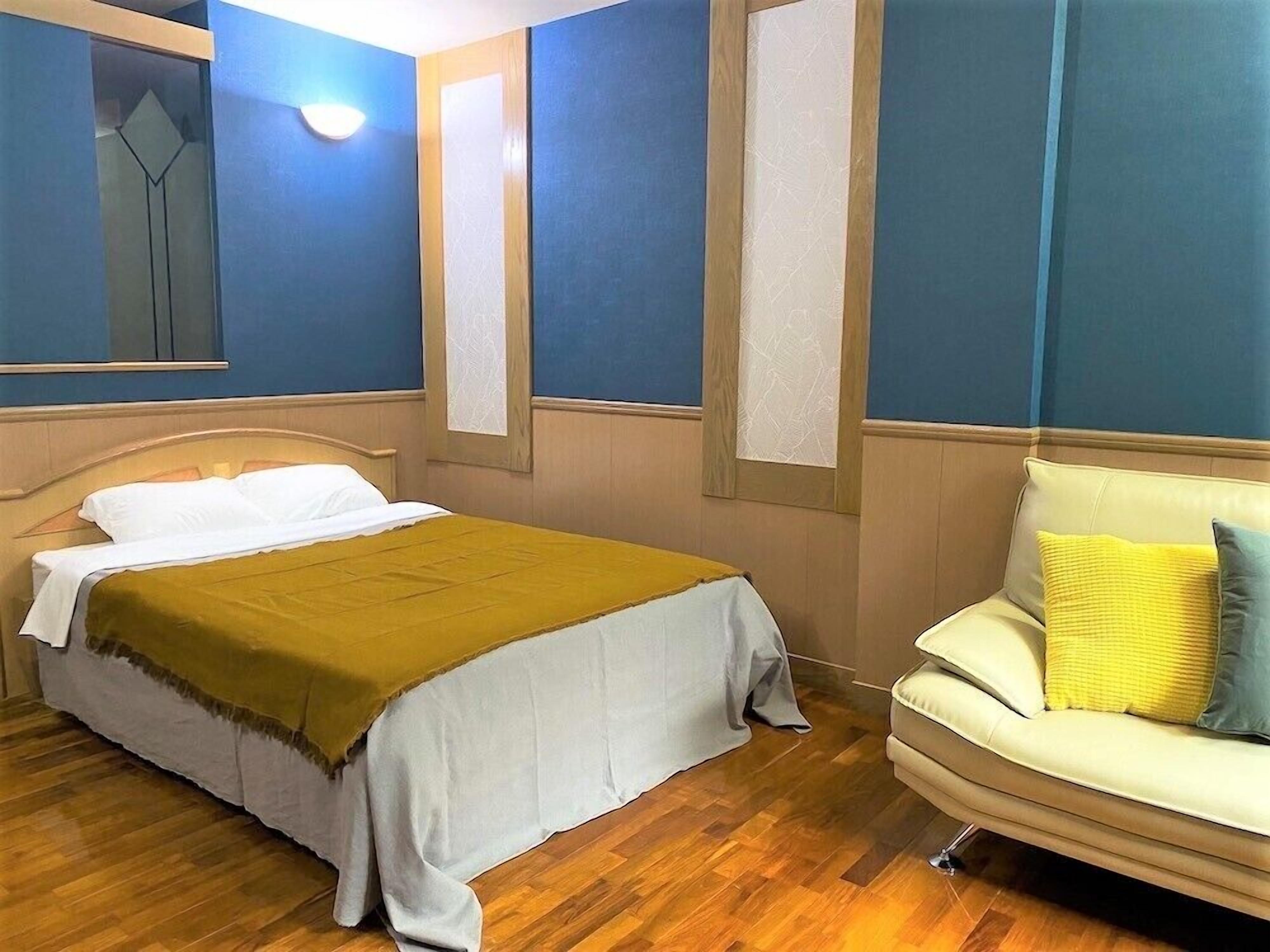 A bedroom with a bed, a chair, and a mirror.