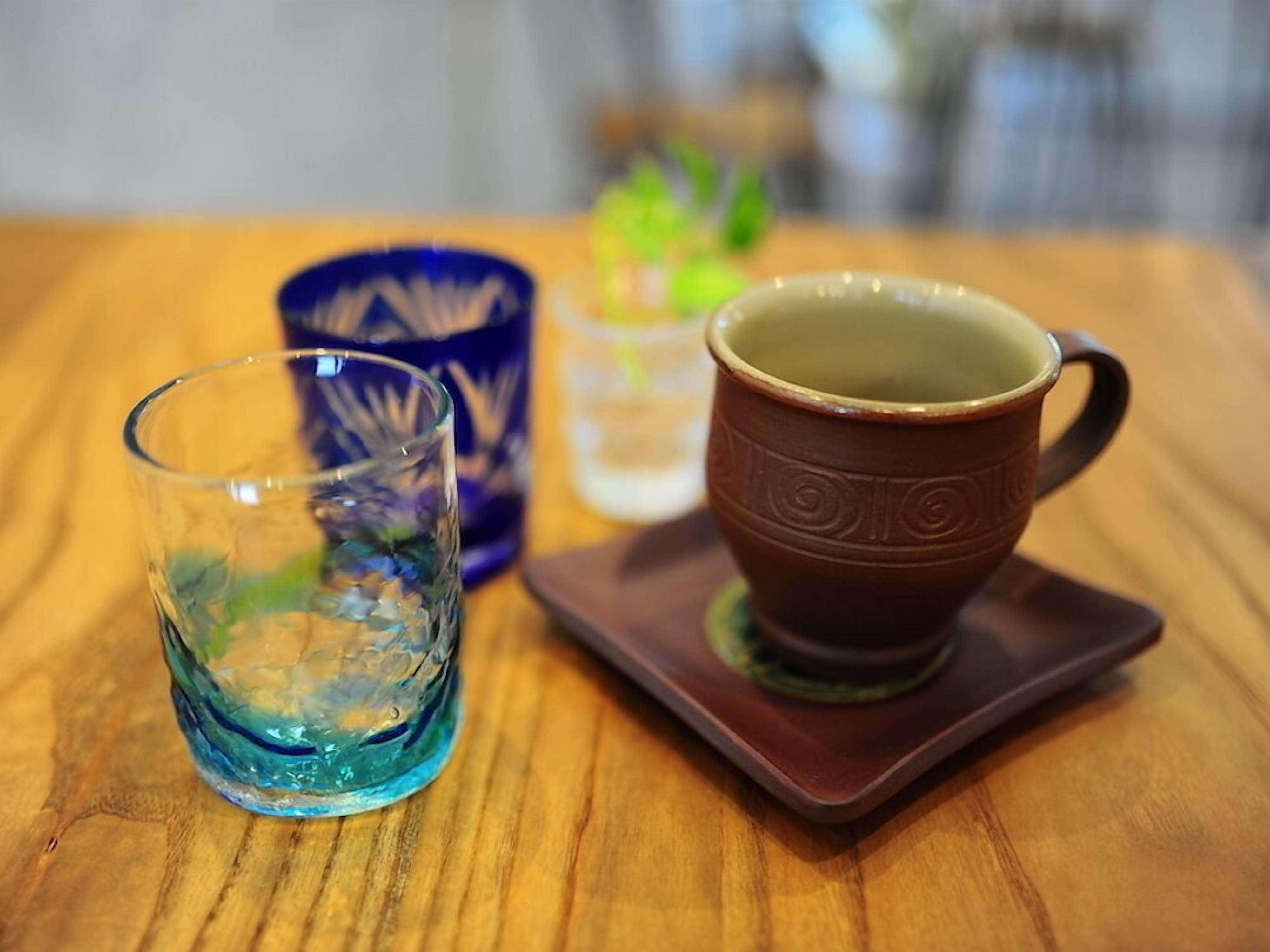A wooden table with two glass cups and a ceramic mug.