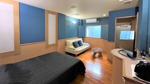 A room with a bed, a small sofa, a mirror, and a window. - Hotel Bin (Okinawa)